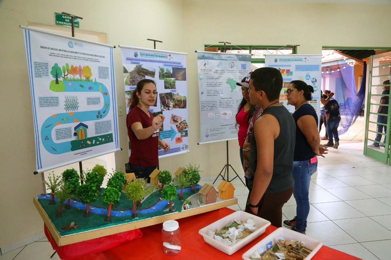 Estudante de posgraduação interagindo com participantes da mostra