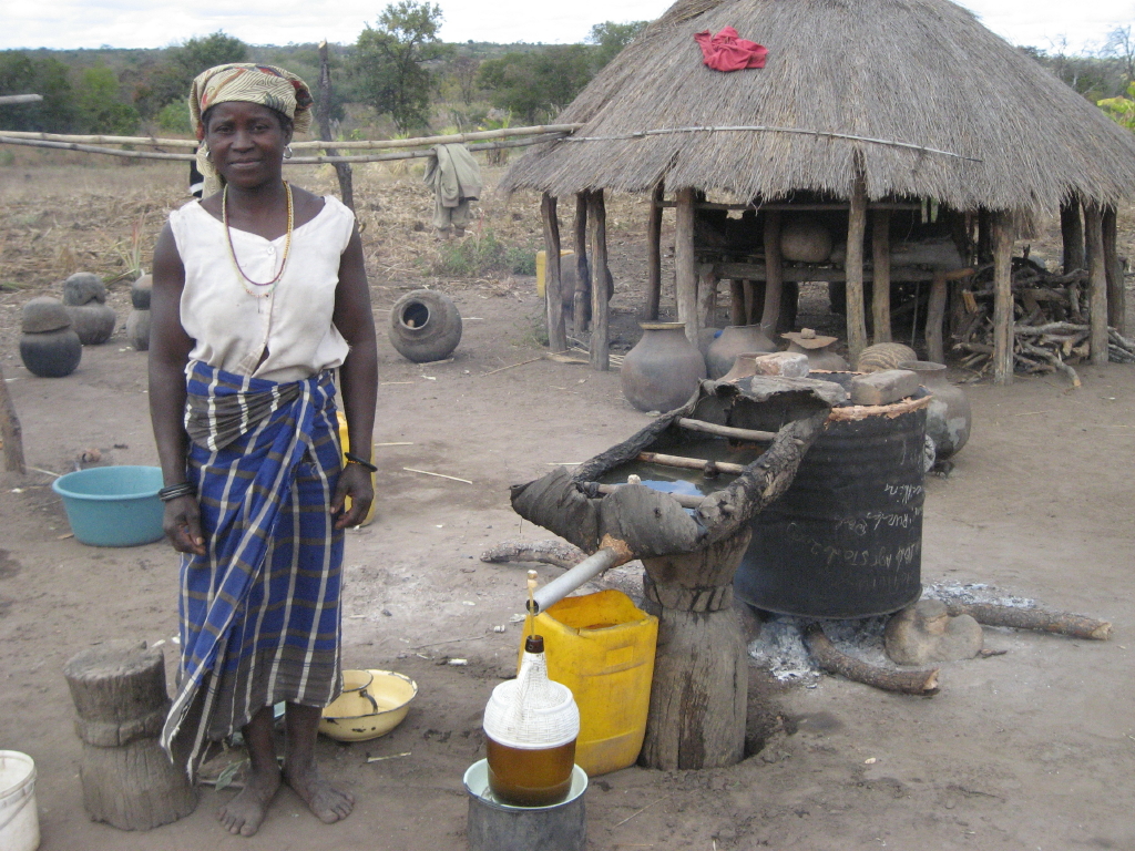 Mujer africana haciendo destilación tradicional en Mozambique Mujer africana haciendo destilación tradicional en Mozambique